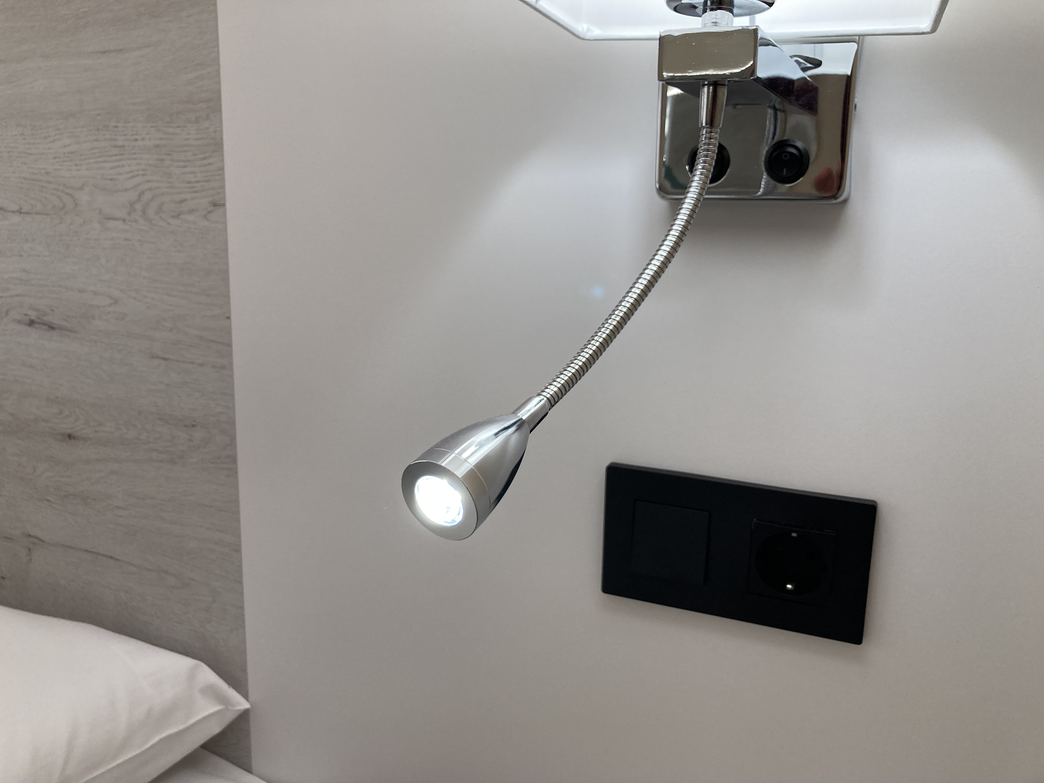 Luz de lectura individual con enchufe junto a la cama